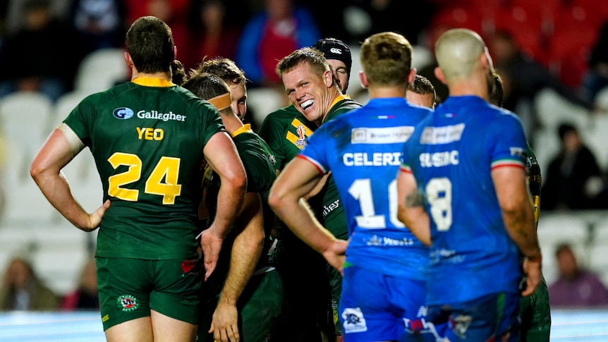 Australia's Lindsay Collins laughs while being embraced by Kangaroos teammates after a Rugby League World Cup try against Italy.
