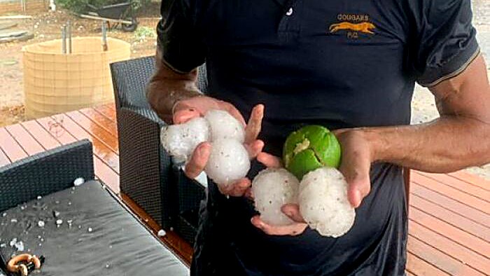 Aaron Edmunds holds hail stones the size of tennis balls and a tennis ball in East Calingiri.