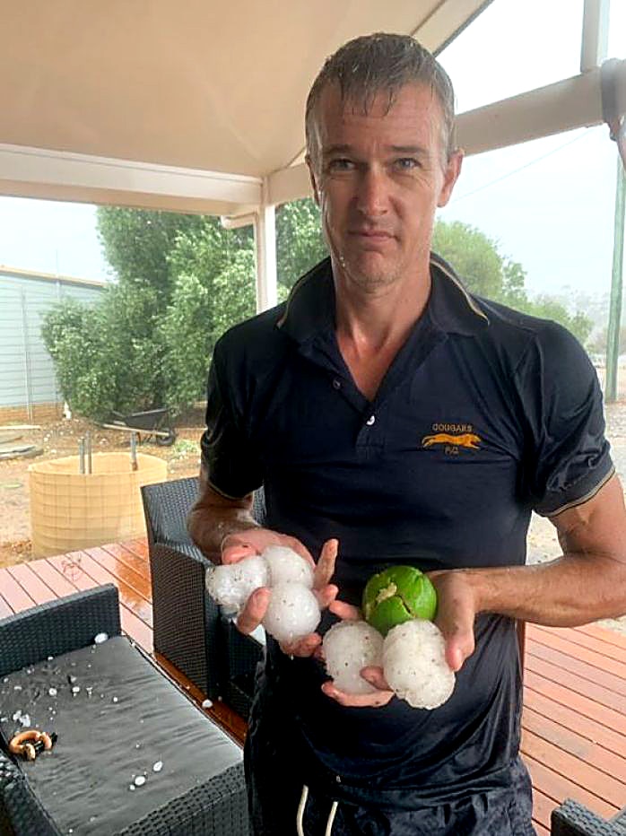 Aaron Edmunds holds hail stones the size of tennis balls and a tennis ball in East Calingiri.