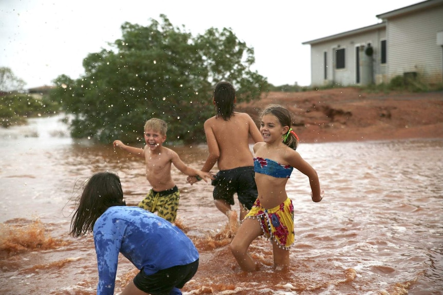 Four children playing in flood waters which had been turned red by the dirt in WA's pilbara.