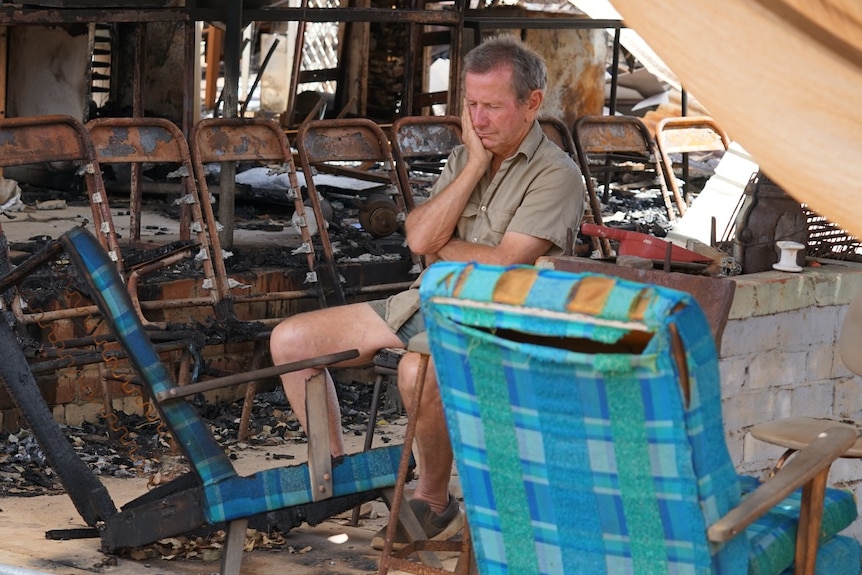 A man sits in a burnt out house