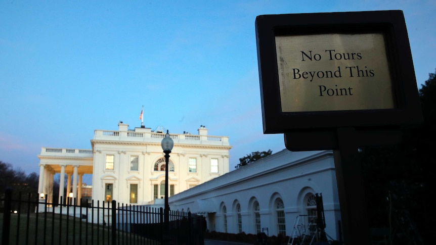 Close shot of a sign with a government building in the background.