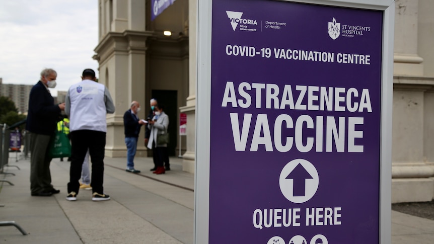 A purple sign directing people to queue for AstraZeneca vaccine.