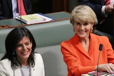 Julia Banks, wearing a white jacket and grey top, sits next to Julie Bishop resplendent in orange. Both women are smiling.