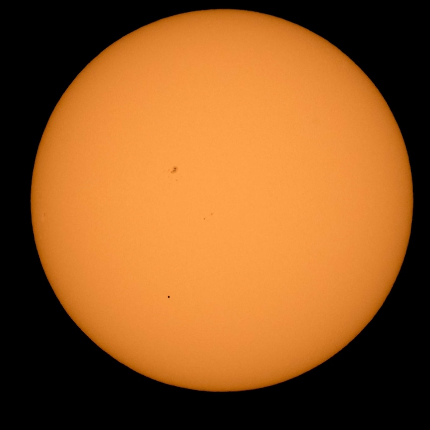 The planet Mercury is seen in silhouette transiting across the sun's face.