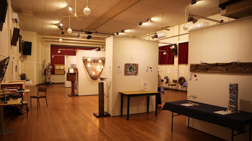 A large community halls with artworks on display on walls around the room.