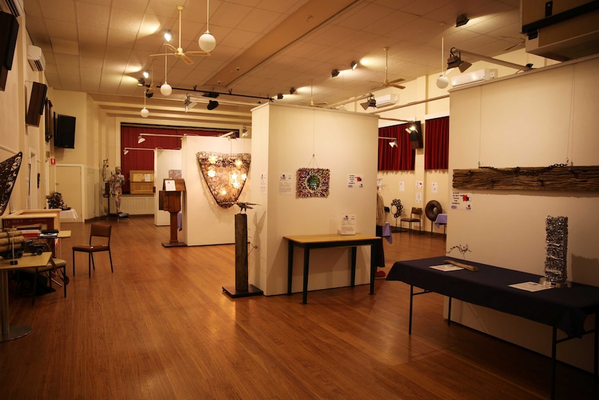 A large community halls with artworks on display on walls around the room.