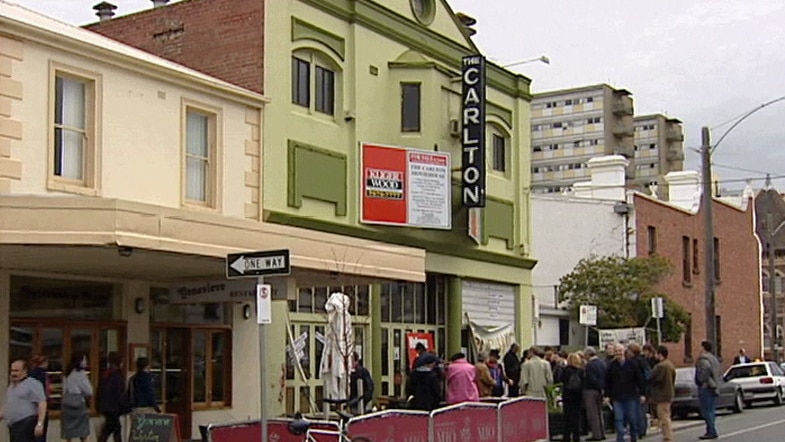 An outdoor shot of a green-painted double-storey Carlton Movie House with a crowd of people spilling off footpath.