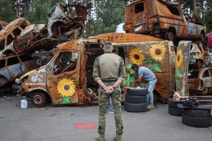 L'uomo dell'esercito guarda i girasoli dipinti a Irbin, in Ucraina