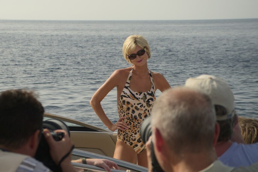 Elizabeth Debicki in character as Princess Diana wearing an animal print swimsuit in a speedboat