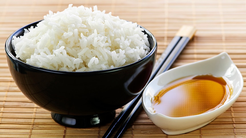 A bowl of white rice with soy sauce.