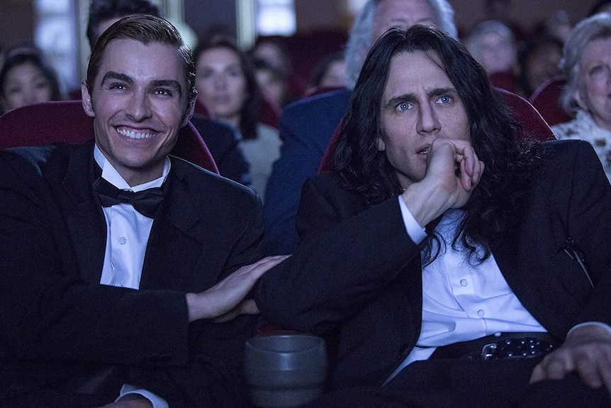 Two men sitting in a dark cinema.