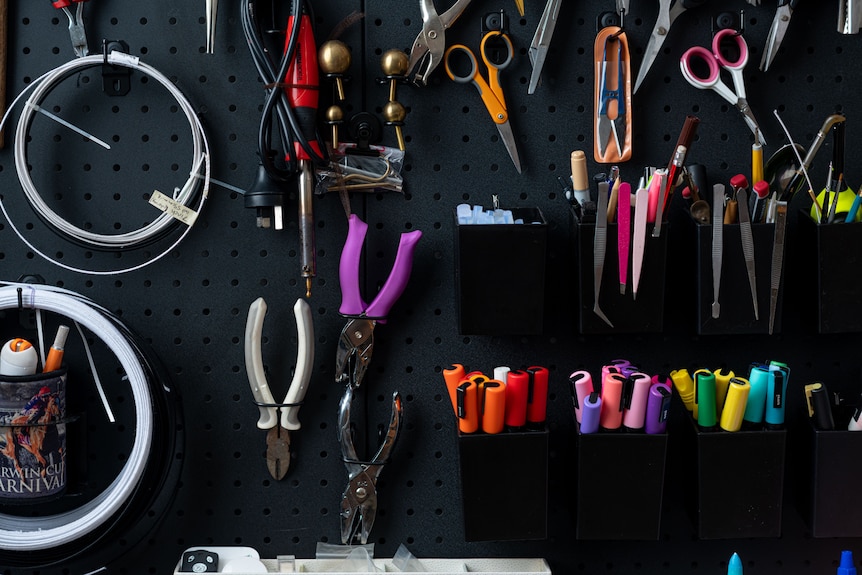 a milliner's tools hang on a black board