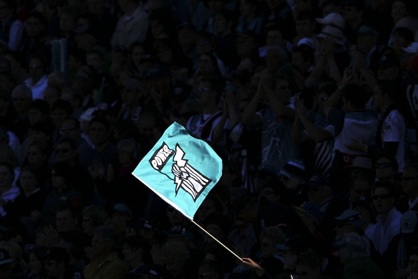 A Port Adelaide flag is waved during an AFL match.