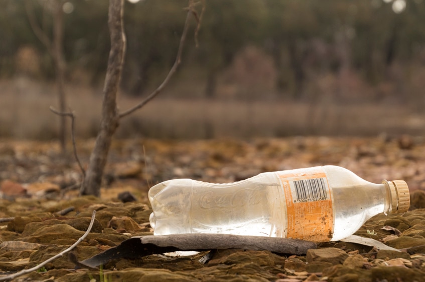 A plastic Coke bottle in the the landscape of Lake Eppalock.