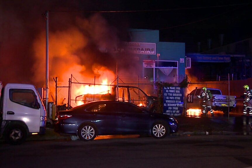 A fire in a building with cars outside on the street.