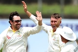 Three Australian cricketers celebrate a Sri Lankan wicket.