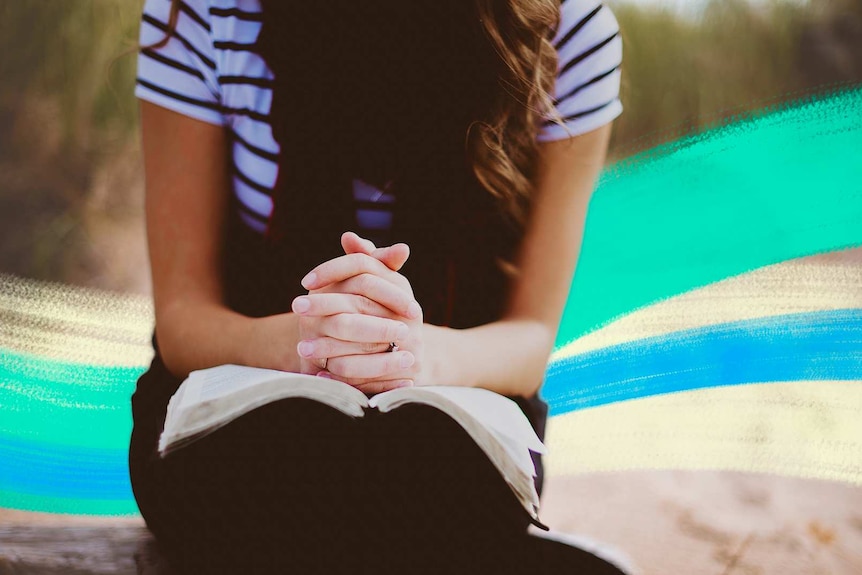 A woman who's face is not shown with her hands clasped together on her lap