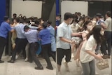 Customers rush out of an Ikea store in Shanghai and authorities try and stop them.