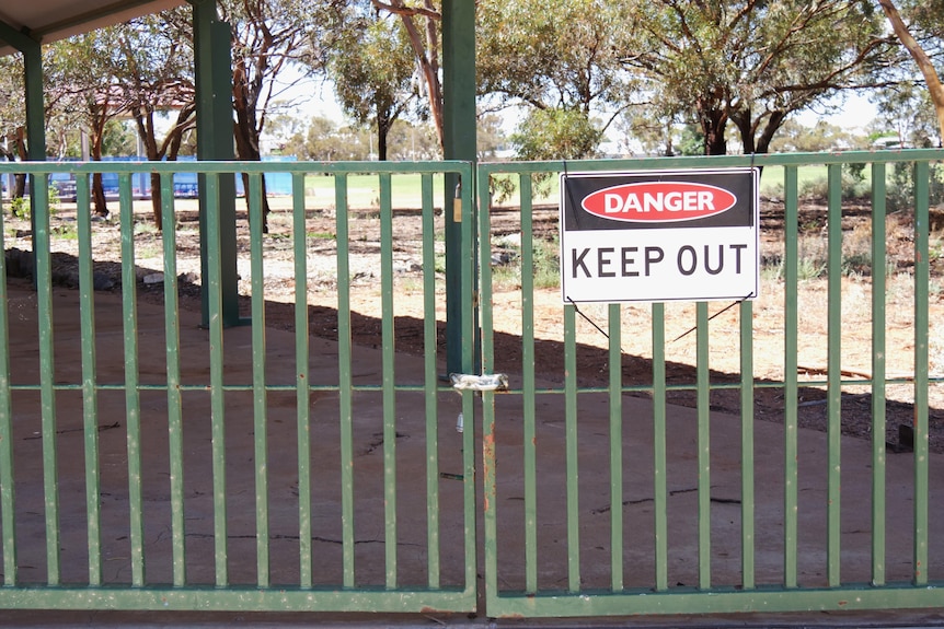 A Danger: Keep Out Sign on a green fence