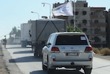 A humanitarian convoy drives through the town of Moadamiyet al-Sham.