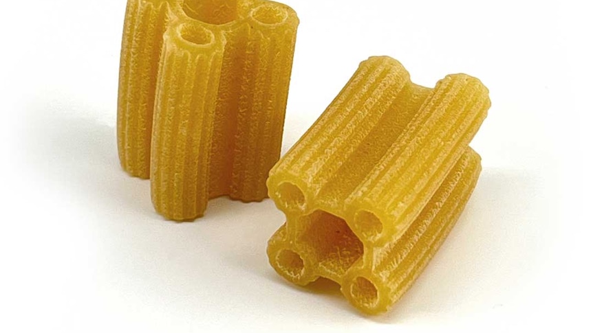 A photo of dried pasta with a hole in it and four smaller holes around it