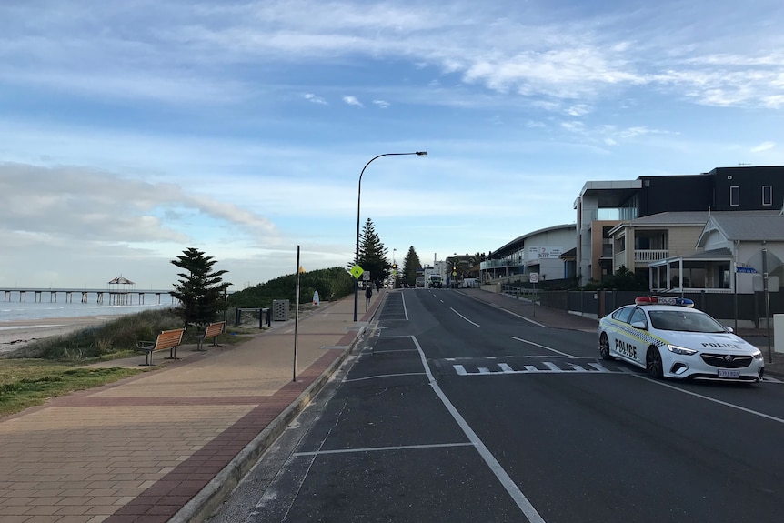 An empty street along the coast apart from a police car