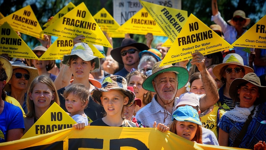 A crowd of protestors hold 'No fracking' signs