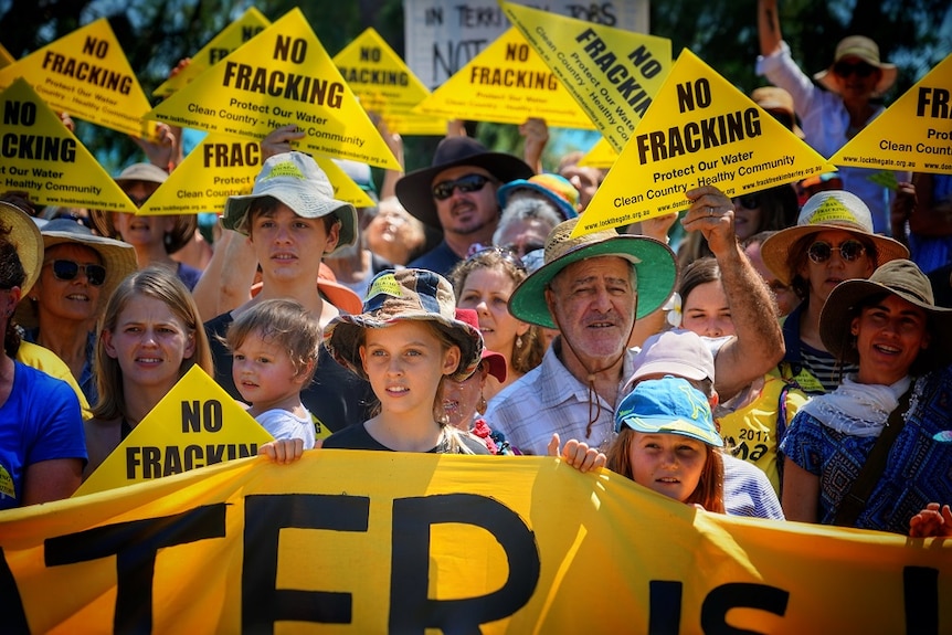 A crowd of protestors hold 'No fracking' signs