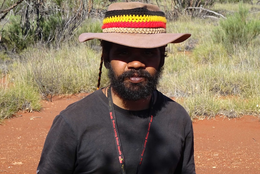 Close-up of Clinton Pryor in the bush wearing a wide-brim hat with colours of the Indigenous flag