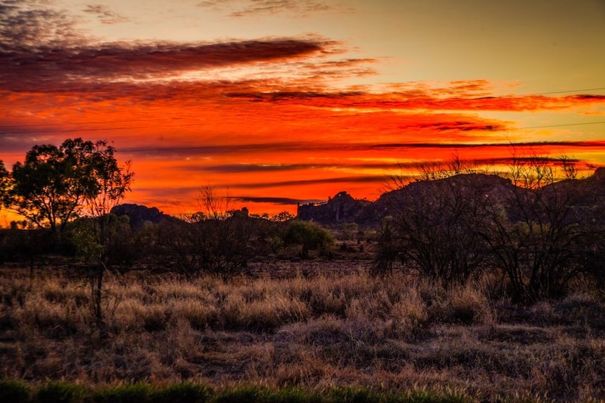 A red sunrise over rocky outcrops in Cloncurry.