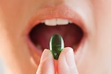 A woman putting a vitamin supplement in her mouth.