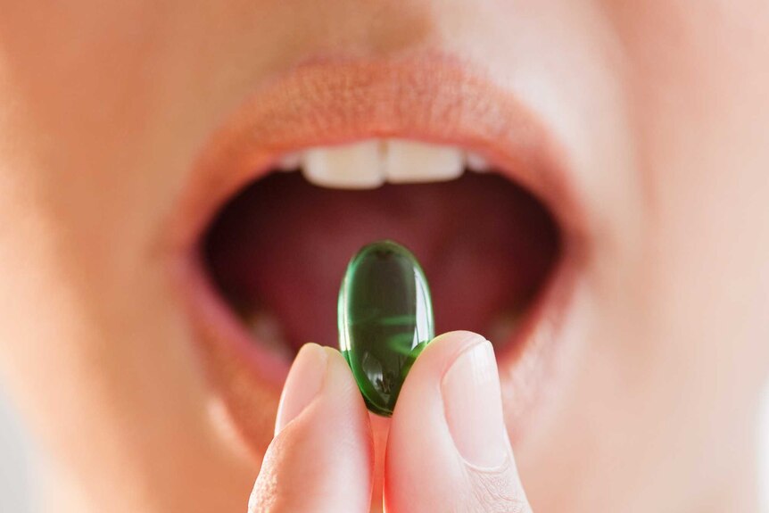 A woman putting a vitamin supplement in her mouth.