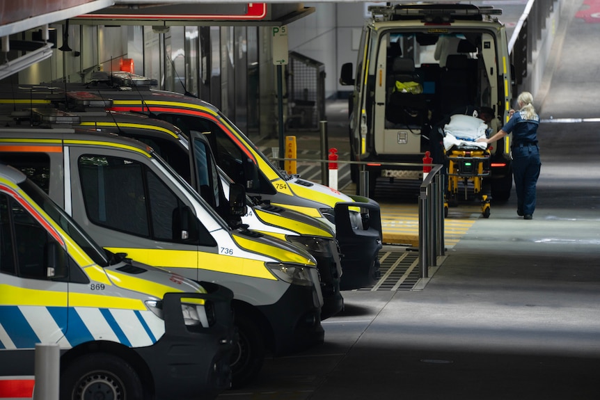 A few ambulances lined up at the bottom of a ramp at a hosptial.