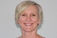 A woman in an orange shirt smiles for the camera.