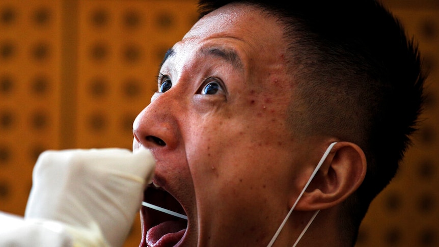A medical staffer takes a swab from a man in Beijing.