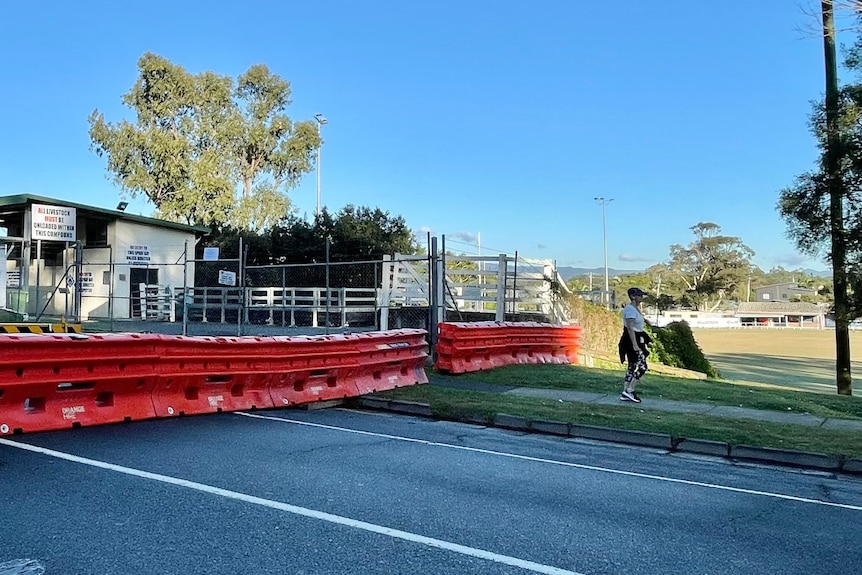 Red barracades blocking off a road, a woman walks through in active wear