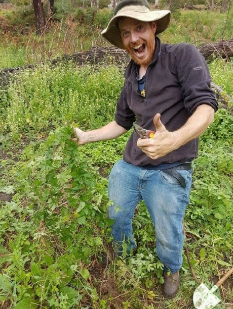 Farmer very excited, holding secateurs and a hops plant.