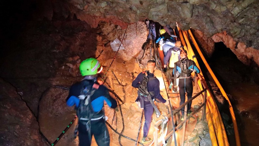 Thai rescue team members walk inside the cave