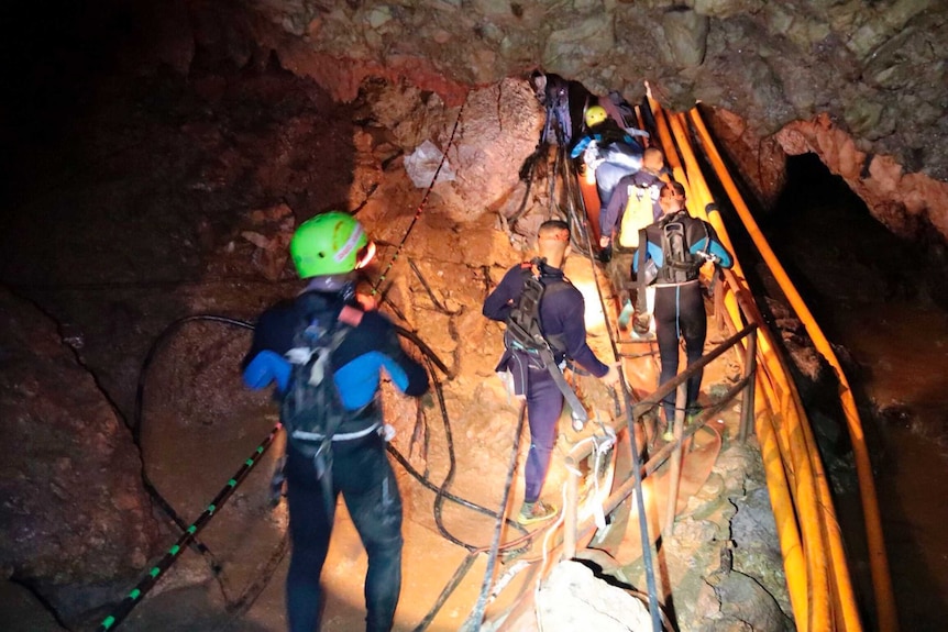 Thai rescue team members walk inside the cave