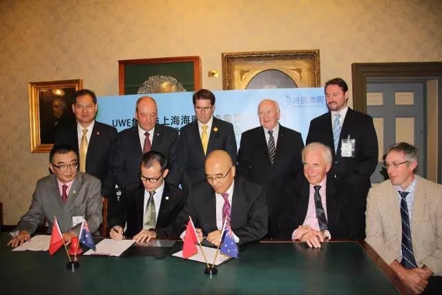 Ten men gather around some men signing a document.