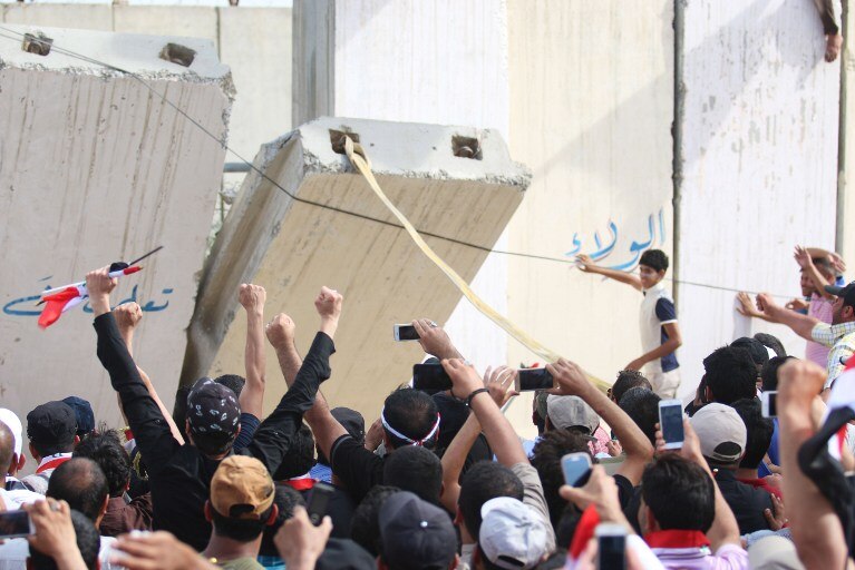 Protesters open a breach in a concrete wall surrounding parliament.