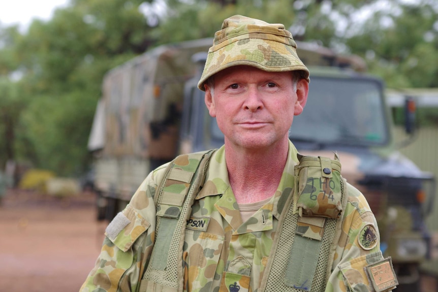 Brigadier David Thompson stands with an army truck in the background.