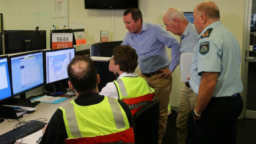 The Premier Mark McGowan stands in a room with other government officials and is briefed on the cyclone.