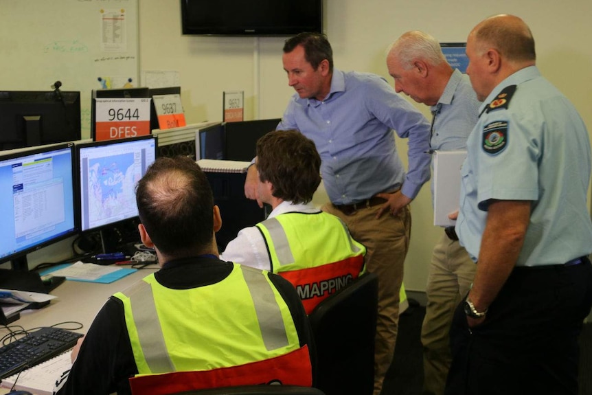 The Premier Mark McGowan stands in a room with other government officials and is briefed on the cyclone.