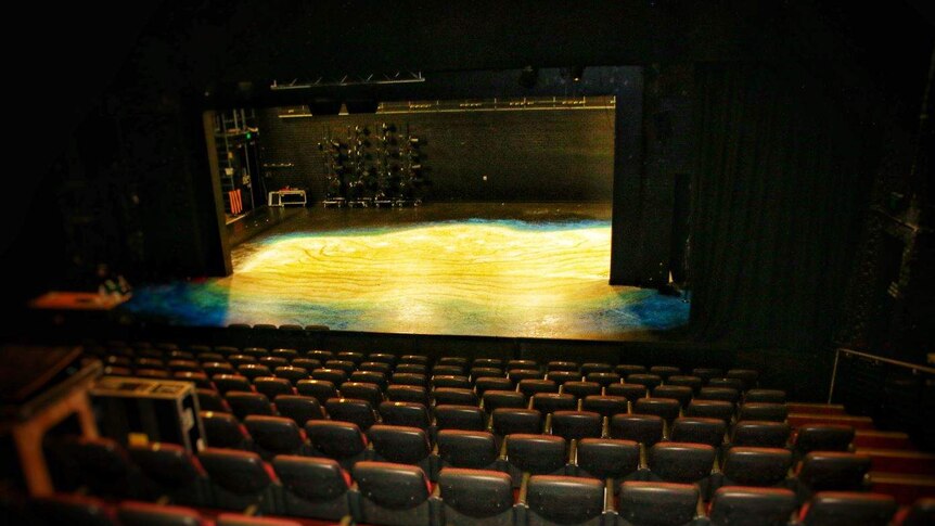 The empty WAAPA theatre with the stage lit up in yellow.