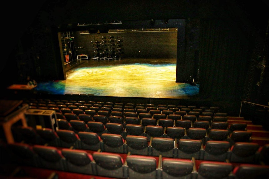 The empty WAAPA theatre with the stage lit up in yellow.