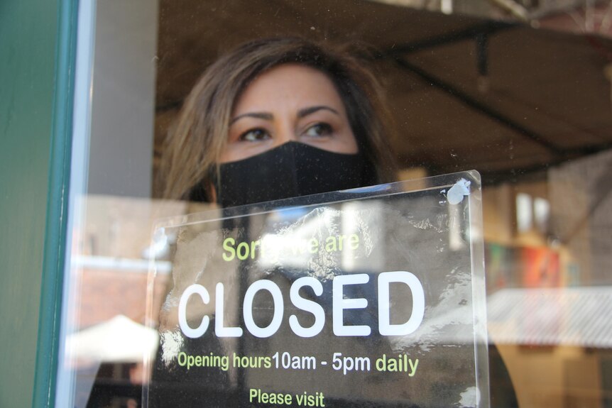 a woman wearing a mask peering put of a window