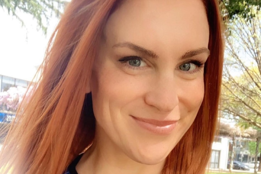 A profile image of a smiling woman with shoulder-length red hair, wearing a blue top.