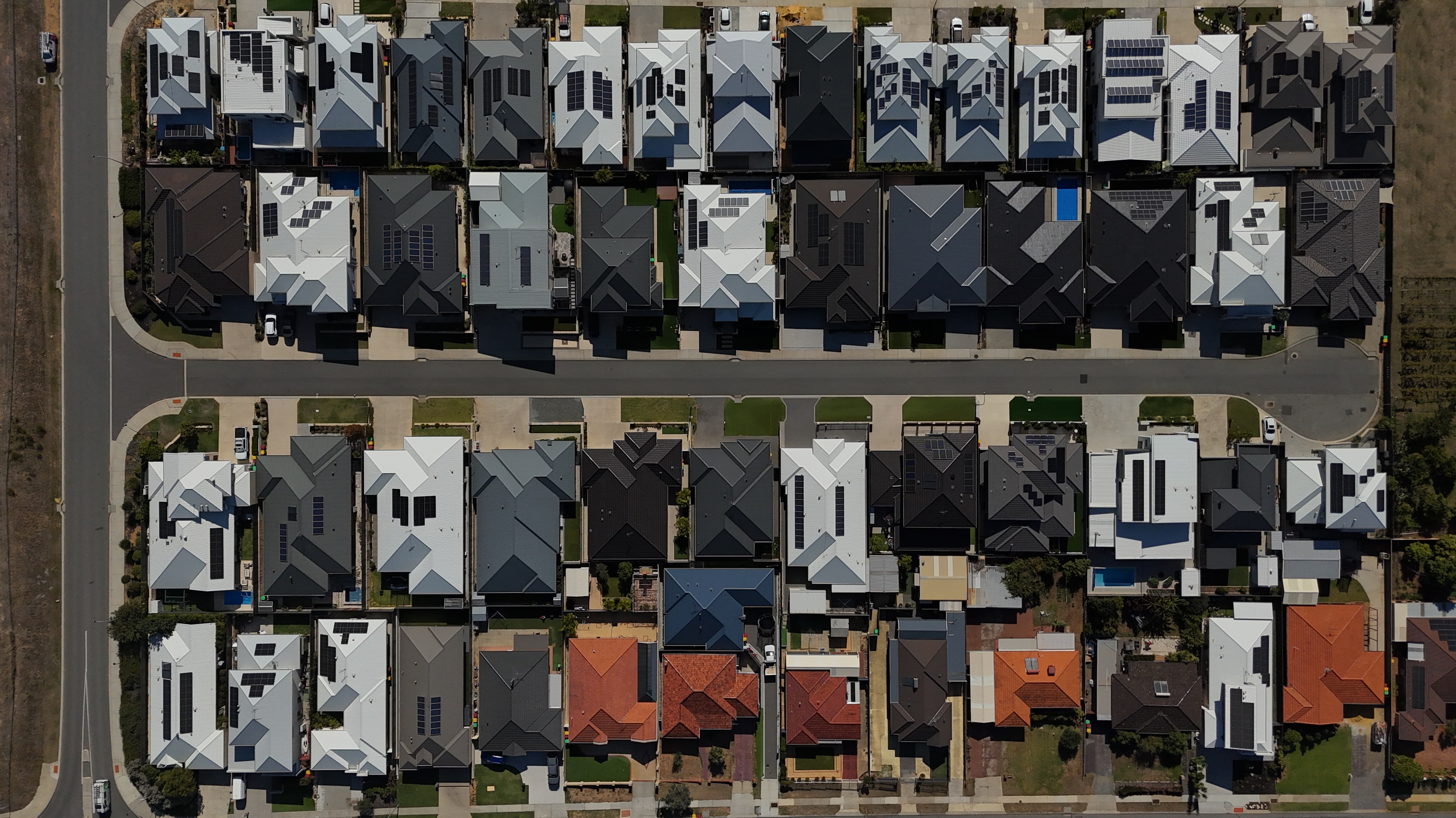 Drone view of a suburb with lots of solar on the houses' roofs. 